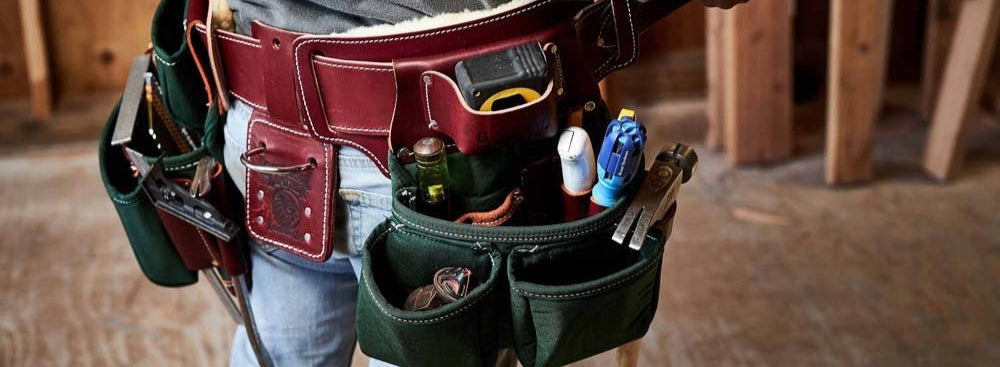 Person wearing a tool belt with various tools in a construction setting